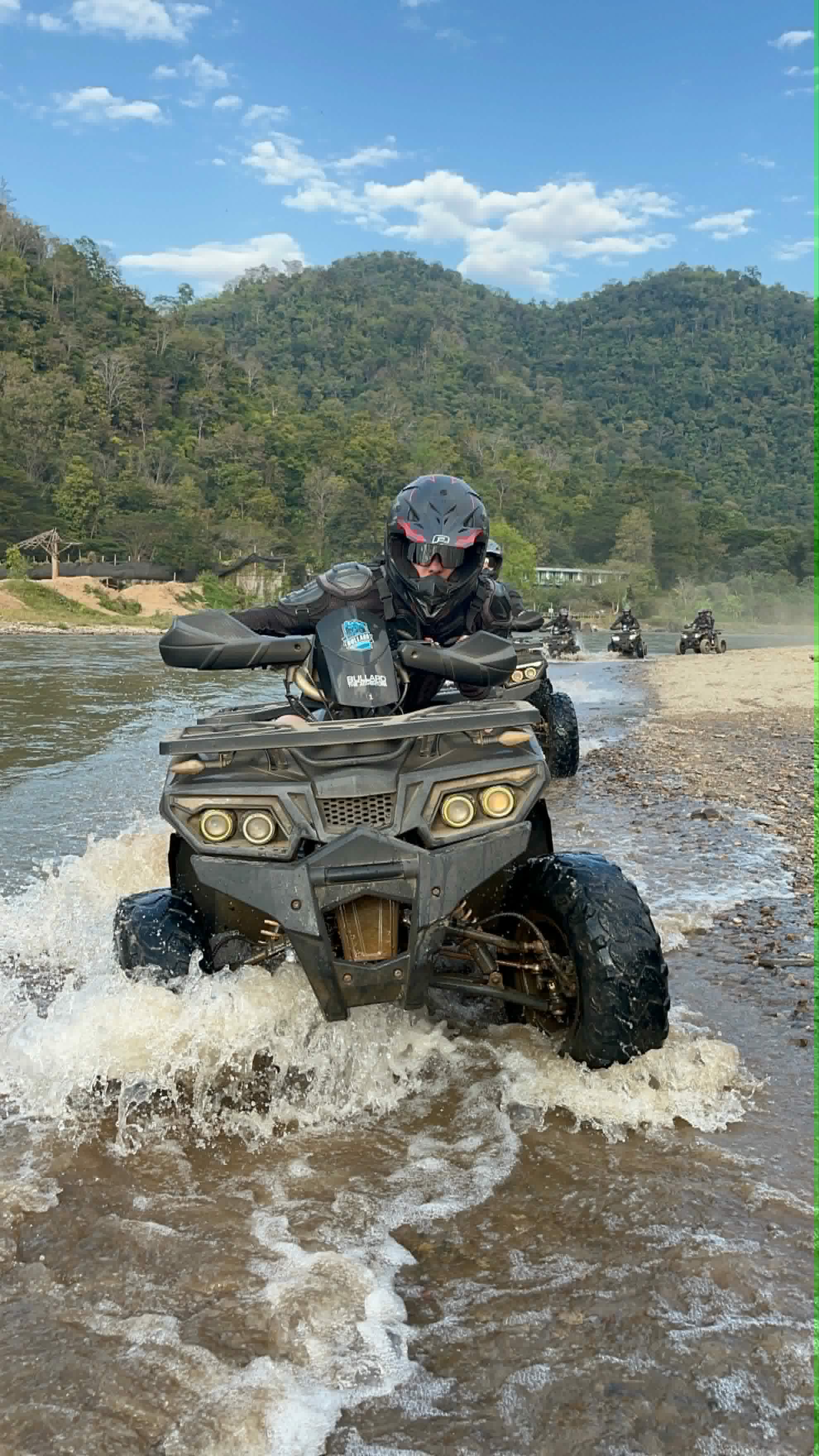 ATV rider splashing through the Mae Taeng river shallows