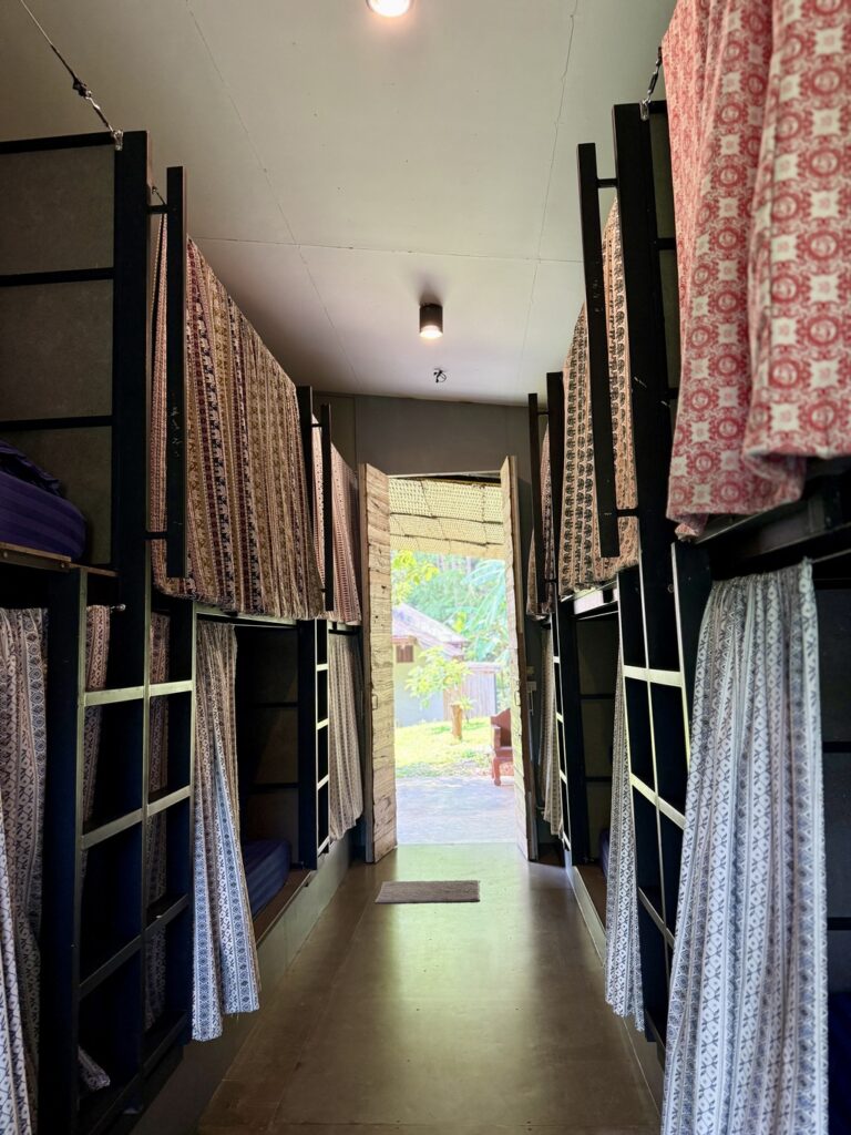 Inside the dorm — bunks with Thai-fabric privacy curtains