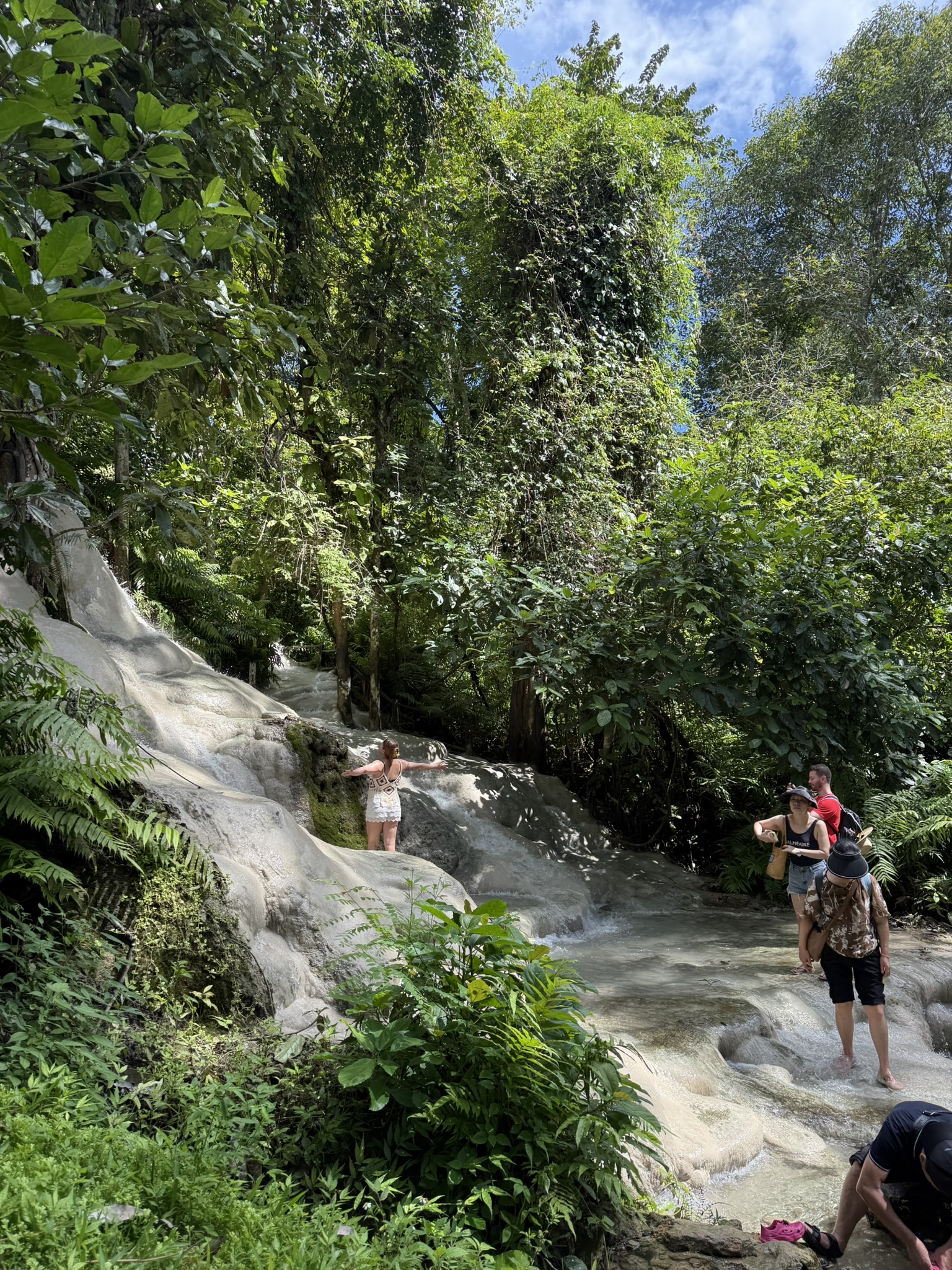 A guest standing on the white limestone of Bua Tong Sticky Waterfall in the afternoon sun
