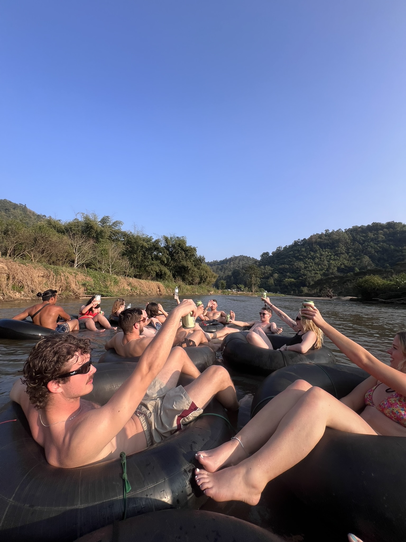 The group raising drinks together mid-river on the sunset tubing social