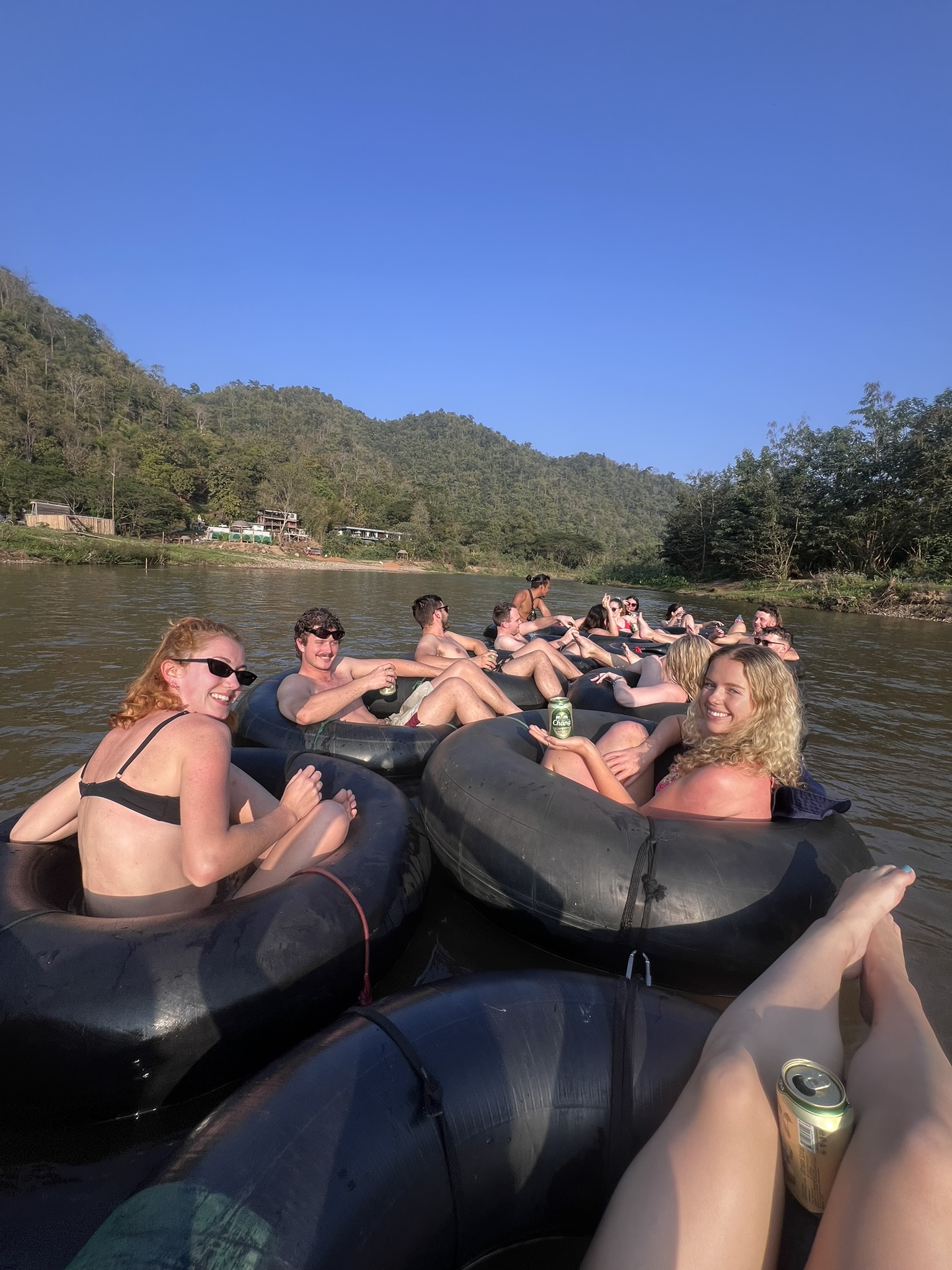 Friends floating side by side in tubes on the Mae Taeng river