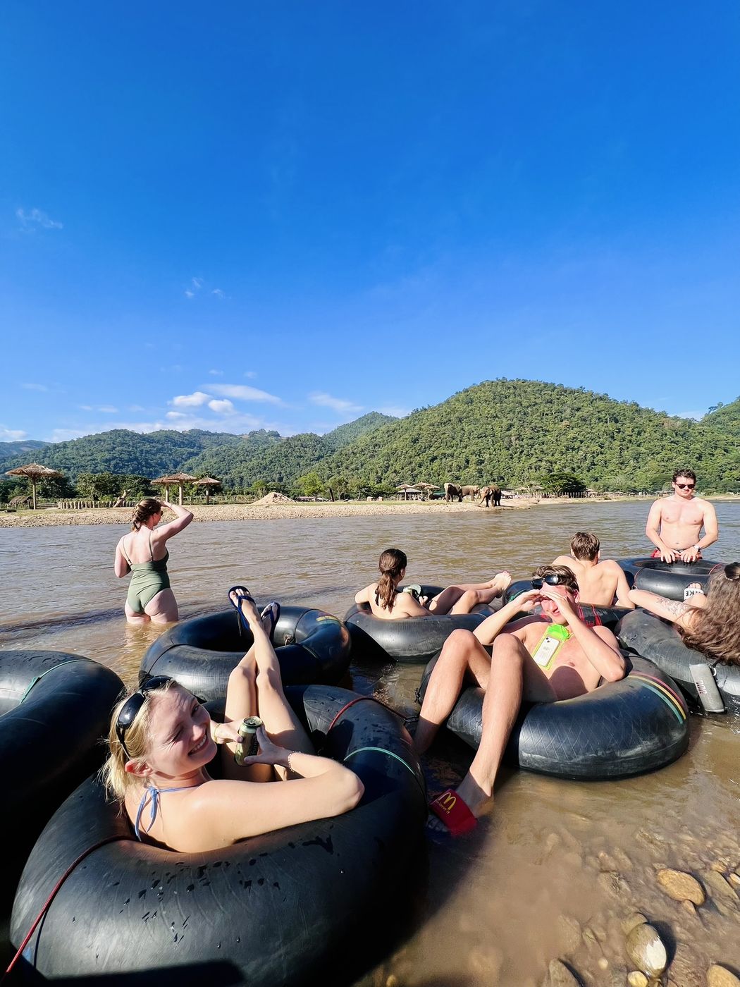 Travellers lying back in their tubes in the shallows with the valley behind them